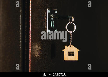 House key with house model keychain in a door. process of opening the front door to the apartment. Stock Photo