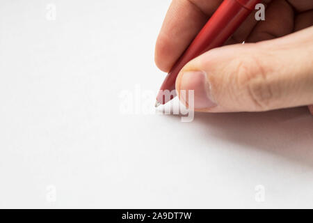 right hand with pencil and left empty over a white blank sheet of paper lying on table. empty space for design. Red pen in hands close up Stock Photo