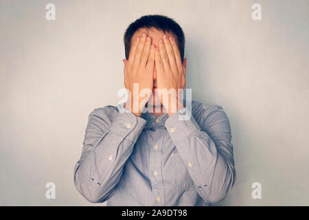 Businessman covers his face with hands. Fatigue and stress at work. The young man covered his eyes with his hands. Hide face. stop seeing Stock Photo