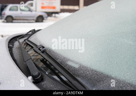 Icy snowflakes on frosty car in cold. windscreen wipers on a car. car janitor froze to the glass of the car at low temperature. Problems with auto in Stock Photo
