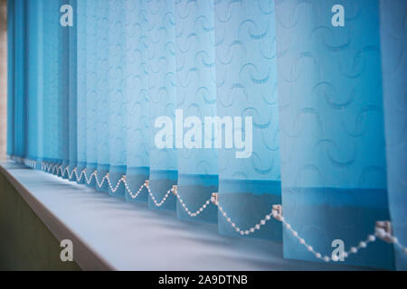 Blue vertical blinds on the long window on the balcony. Modern interior design. Closed window from sunlight Stock Photo