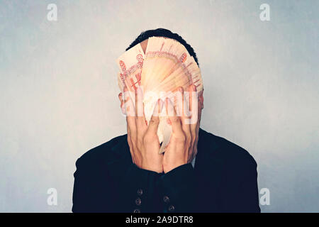 close-up view of man holding russian rubles banknotes in hand. 5000 banknotes folded fan cover the face of the businessman. young successful man washe Stock Photo