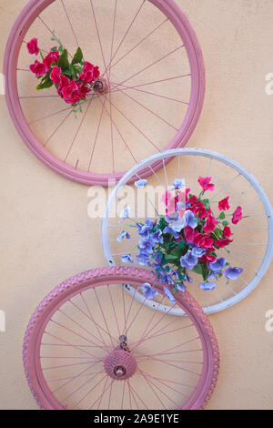 decorated bicycle wheels hanging on the wall of a house Stock Photo