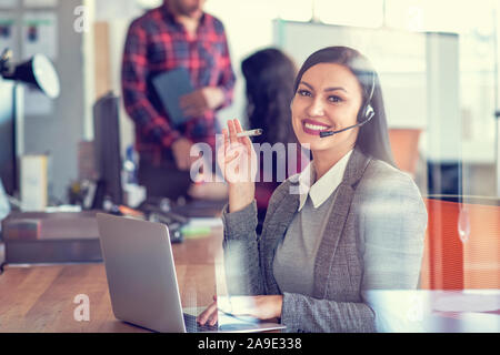 Beautiful call center agent browsing the internet on her computer Stock Photo