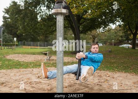 Young man having fun on swing on the playground in germany europe. Stock Photo