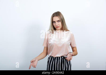 Beautiful lady pointing down with fingers showing advertisement, surprised face Stock Photo
