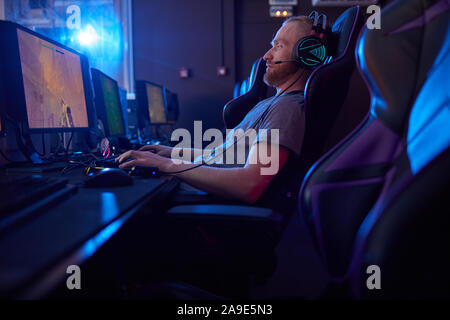 Premium Photo  Rear view play video computer pc. young man sitting on  chair in game station. happiness streamer indian man wearing headphone playing  game online in the darkroom.