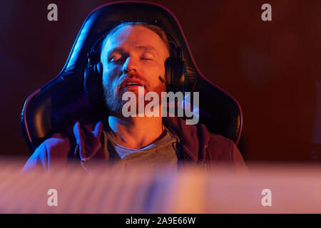 Young bearded man in headphones sitting in gaming chair and sleeping he tired after game Stock Photo