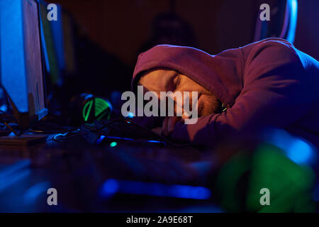 Young computer programmer lying on the desk in front of computer monitor and sleeping he working till late night Stock Photo