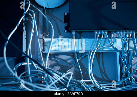 Close-up of computer system with white cables hanging on the wall in dark office Stock Photo