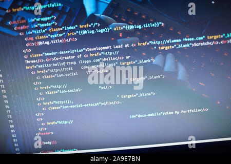 Close-up of man typing computer codes and reading them on computer monitor Stock Photo