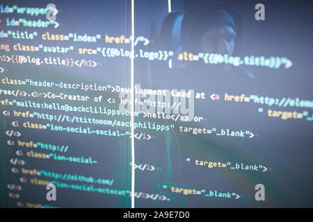 Image of computer symbols on black computer monitor with computer hacker's reflection on it Stock Photo