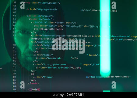 Close-up of computer screen with codes and symbols with computer hacker in black clothing in the background Stock Photo