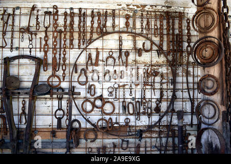 A wall full of old chains and farm implements and tools Stock Photo