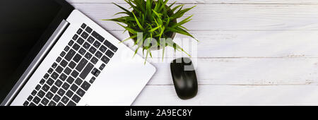 Working place on white wooden table with copy space. Laptop, mouse, phone, flower in a pot. Flat lay. Top view of blackboard office desk Stock Photo