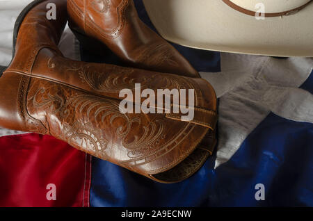 Cowboy hat and boots represent a way of life in the great state of Texas by resting on the Lone star state flag. Stock Photo