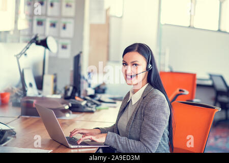 Beautiful call center agent browsing the internet on her computer Stock Photo
