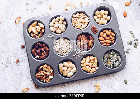 Various nuts and seeds on white background. Nuts assortment frame - pecans, hazelnuts, walnuts, pistachios, almonds, peanuts, pumpkin and sunflower se Stock Photo