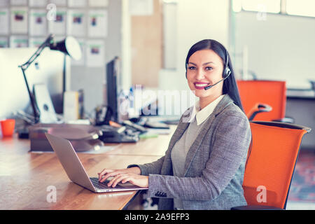 Beautiful call center agent browsing the internet on her computer Stock Photo