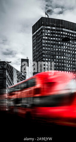 Driving red bus in front of skyscraper Stock Photo