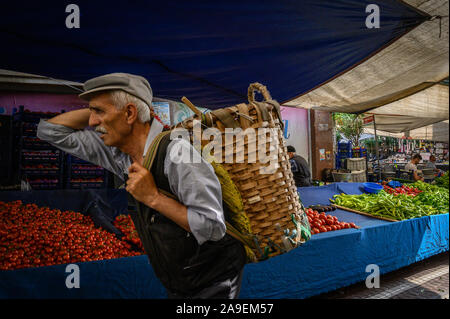 Man carrying a basket in the Fatih Market, Istanbul, Turkey Stock Photo