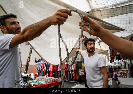 Men setting up shop by putting up tarps in the Fatih Market, Istanbul, Turkey Stock Photo