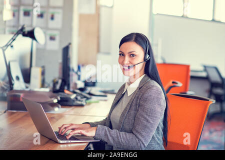 Beautiful call center agent browsing the internet on her computer Stock Photo