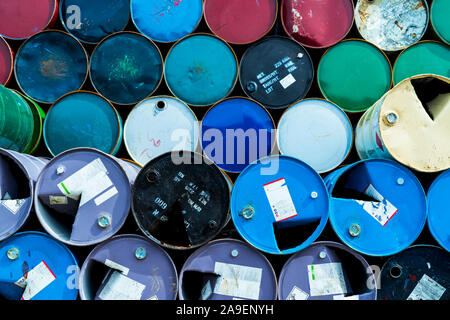 Old chemical barrels. Blue, green, and red oil drum. Steel oil tank. Toxic waste warehouse. Hazard chemical barrel with warning label. Industrial Stock Photo