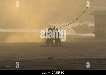 Military team in conflict rescuing people by helicopter. Getting loaded on a rope attached to chopper in the smoke and haze in the Middle East conflict Stock Photo