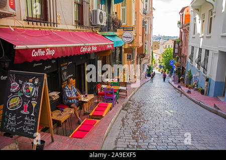 Istanbul, Turkey - September 6th 2019. A tourist enjoys  coffee at a cafe in a small road in the Kabatas quarter of Beyoglu on the European side of Is Stock Photo