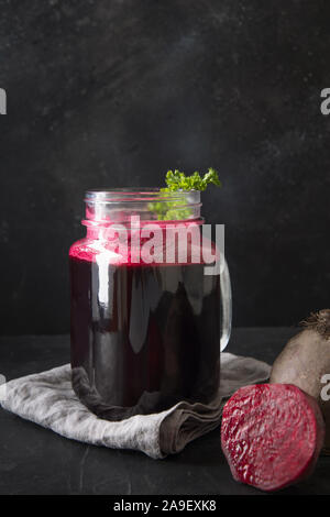 Glass of fresh beetroot juice garnish parsley on black table. Close up. Vertical orientation. Stock Photo