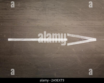 Flat lay picture of white arrow on a gray asphalt - Aerial drone top down view of white arrow on asphalt Stock Photo