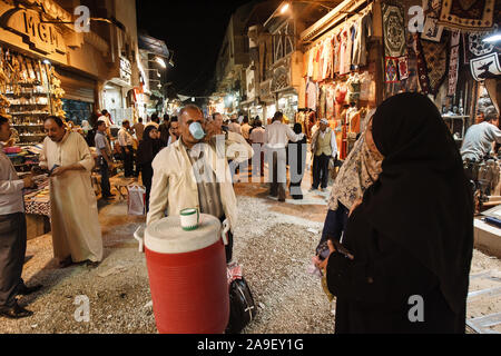 Cairo, Egypt, May 2, 2008: A man drinks water from a  cooler in the middle of a busy street in the Khan el-Khalili bazaar in Cairo. Stock Photo