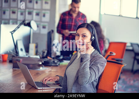 Beautiful call center agent browsing the internet on her computer Stock Photo