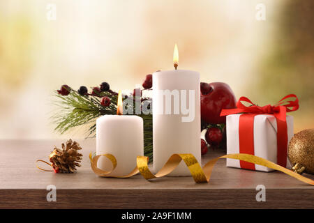 Two burning candles on Christmas wooden table with gift. Front view. Horizontal composition Stock Photo