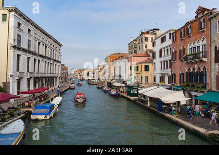 Venice, Italy - September 27, 2013: View on Cannaregio Canal with boats and fruit market on the embankment on sunny morning Stock Photo