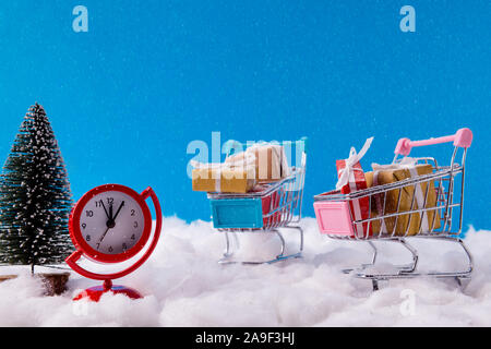 Christmas season buyer shopping concept. Small trolley have red brown yellow gift boxes prepare x-mas celebration dont want late watch red clock stand Stock Photo