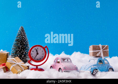 Christmas presents delivering. Santa claus ad his small helper drive pink blue cars from snowy north-pole hurry for countdown watch red clock near Stock Photo