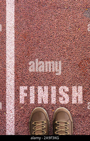 Word Finish written on rubber sports track background. Foot and legs seen from above. Selfie great for any use. Finish Line for the concept of accompl Stock Photo