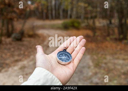 Traveler holding compass and looking for the road in forest Stock Photo