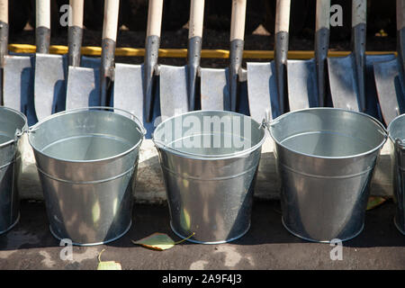 Buckets and shovels prepared for cleaning the streets. Metal buckets without water. Garden tools for sale. Preparing tree planting. Metal products. Stock Photo