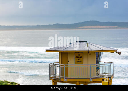 Surf rescue tower, lifesavers watchtower on Elouera beach with view of Kurnell on overcast morning. Cronulla, Australia Stock Photo