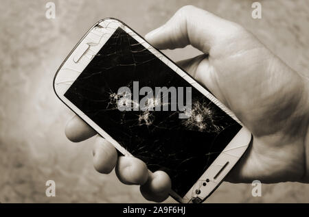 Male hand holding up a smartphone with the broken display. Stock Photo