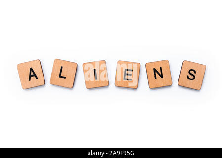 The word ALIENS, spelt with wooden letter tiles over a white background. Stock Photo