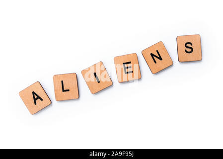 The word ALIENS, spelt with wooden letter tiles over a white background. Stock Photo