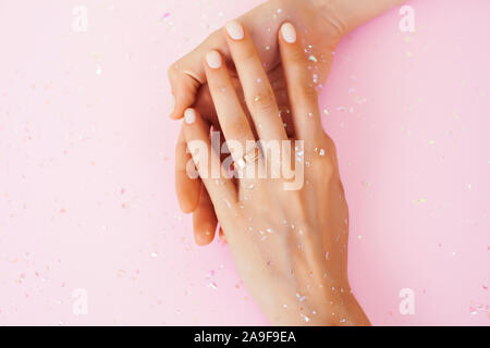 beautiful manicured woman hands on pink background, wearing wedding ring