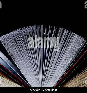 Lots of colourful thick open books stand on a dark background Stock Photo