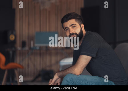 Young attractive guy sitting relaxing on a sofa in his loft office Stock Photo