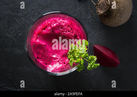Glass of fresh beetroot juice garnish parsley on black table. Top view. Close up. Stock Photo