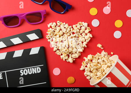 Heart laid out from popcorn, clapperboard, 3d glasses and bucket on red background Stock Photo